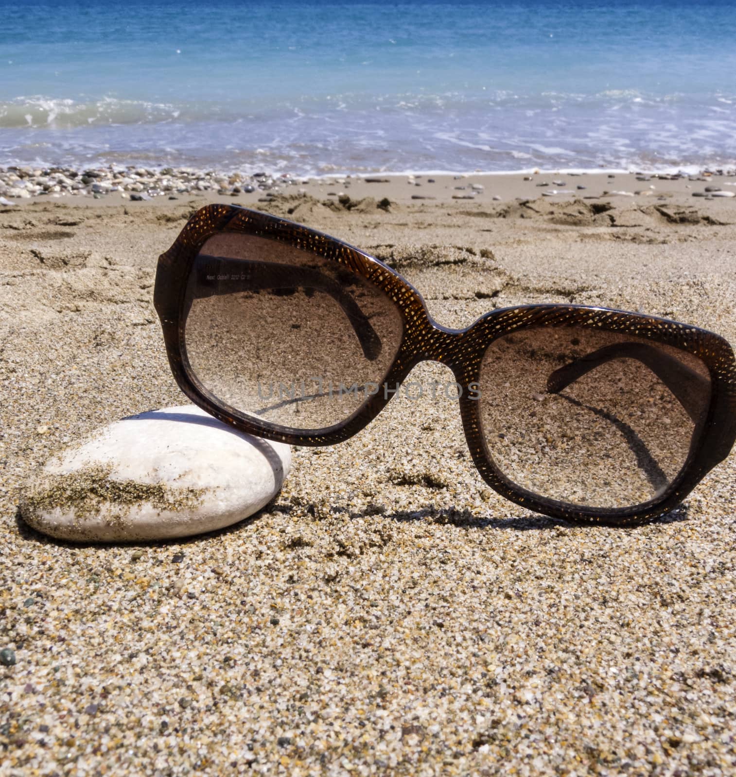 Sunglasses lying on rocky beach. Sunglasses on the beach.