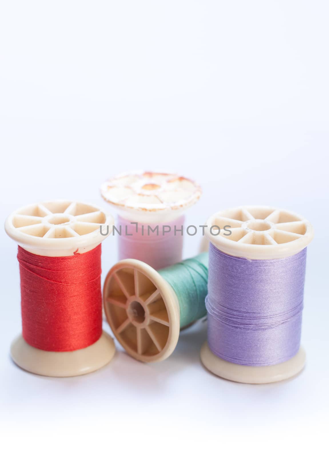 Vintage grunge colorful thread spool on white background, stock photo