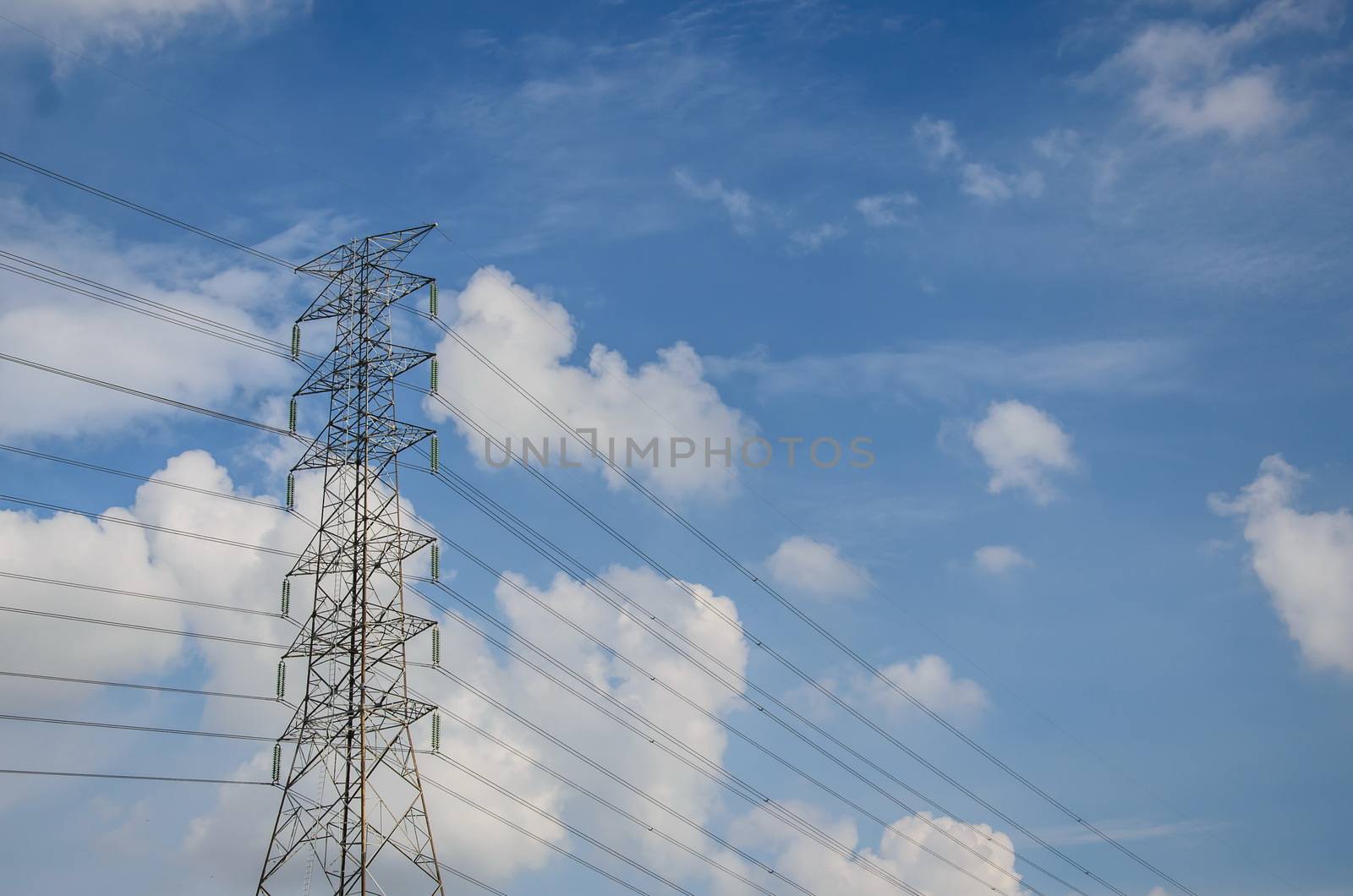 High voltage tower and electric line over cloudy blue sky in Thailand