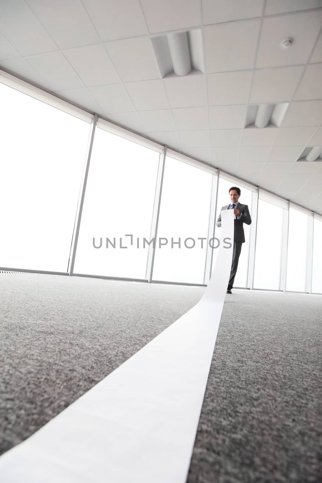 Office worker unrolling long sheet of paper