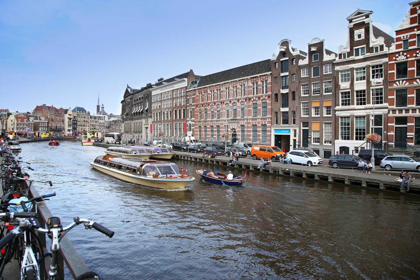 AMSTERDAM, THE NETHERLANDS - AUGUST 19, 2015: View on Rokin from bridge Doelensluis. Street life, Canal, tourists, bicycle and boat in Amsterdam. Amsterdam is capital of the Netherlands on August 19, 2015.