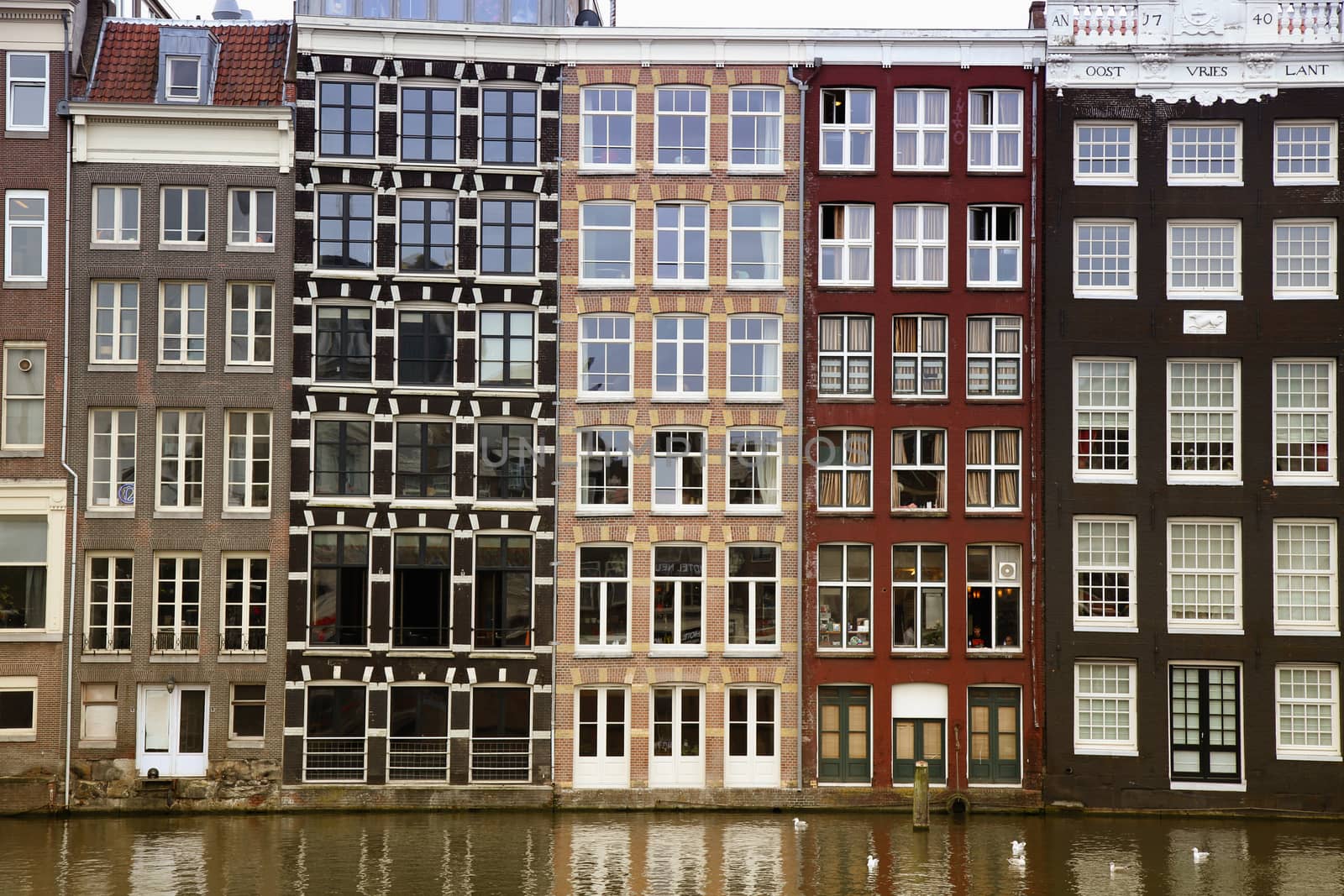 AMSTERDAM; THE NETHERLANDS - AUGUST 16; 2015: Beautiful views of the ancient buildings at the waterside, Damrak canal in Amsterdam. Amsterdam is capital of the Netherlands on August 16; 2015.
