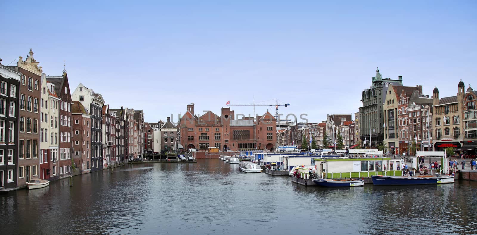 AMSTERDAM; THE NETHERLANDS - AUGUST 16; 2015: Beautiful views of the ancient buildings at the waterside, canal and boats, Damrak canal in Amsterdam, The Netherlands on August 16; 2015.