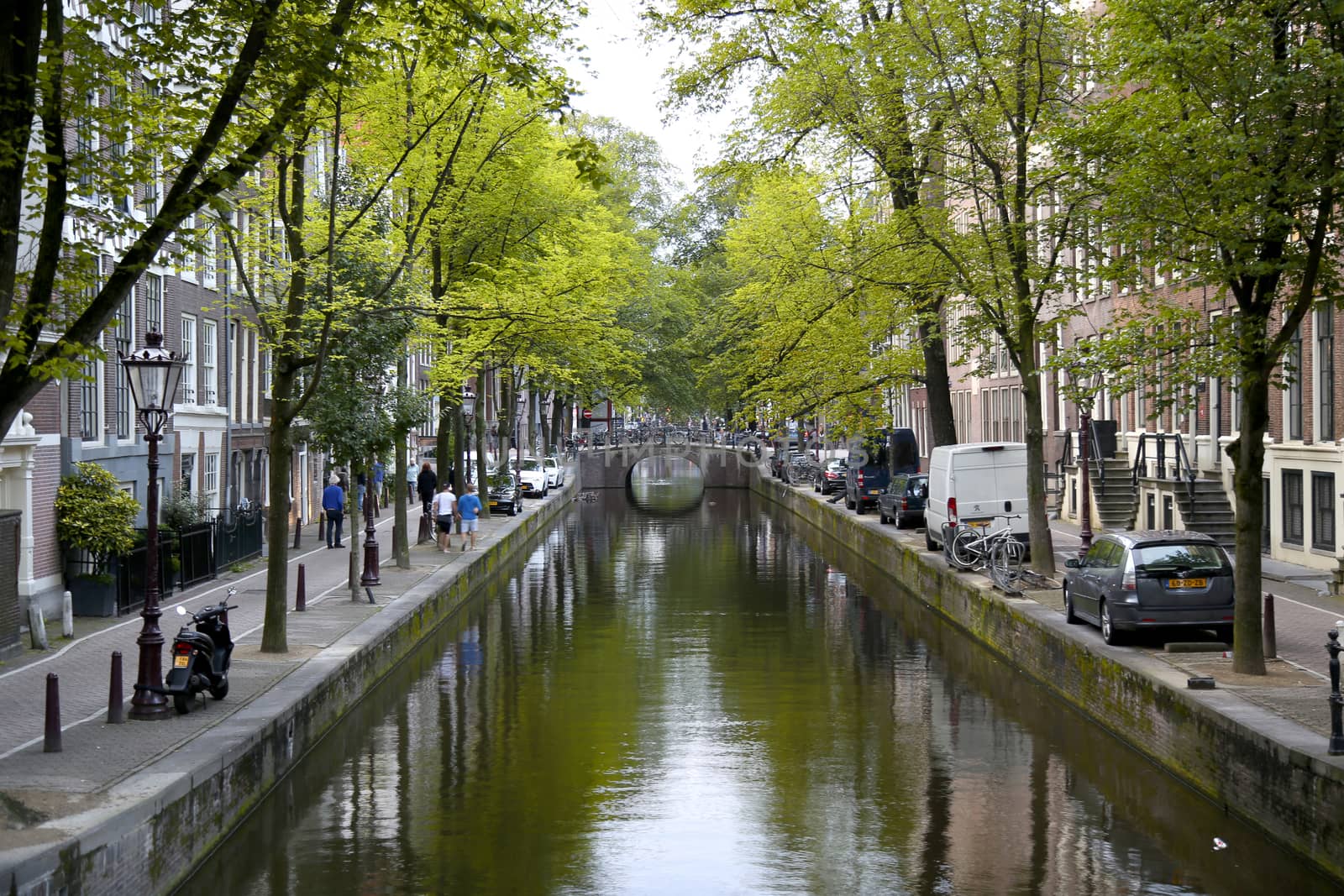 AMSTERDAM; THE NETHERLANDS - AUGUST 18; 2015: View on beautiful street Oudezijds Achterburgwal, street life, canal and tourists. Amsterdam is capital of the Netherlands on August 18; 2015.