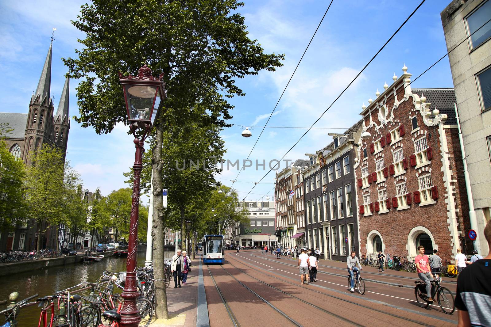 AMSTERDAM; THE NETHERLANDS - AUGUST 19; 2015: View of Singel street and De Krijtberg church from Koningsplein. Street life, canal, pedestrians, tram and bicycle, Amsterdam is capital of the Netherlands on August 19; 2015.