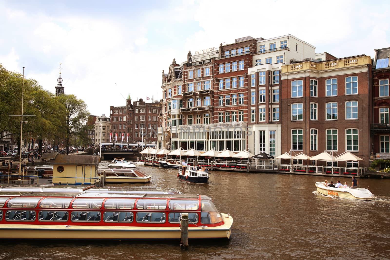 AMSTERDAM, THE NETHERLANDS - AUGUST 19, 2015: View on Hotel de l'Europe and Amstel street from Halvemaansbrug. Street life, Canal, bicycle and boat in Amsterdam. Amsterdam is capital of the Netherlands on August 19, 2015.