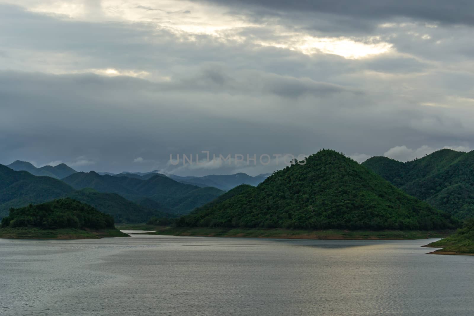 landscape with mountains trees and a river in front.