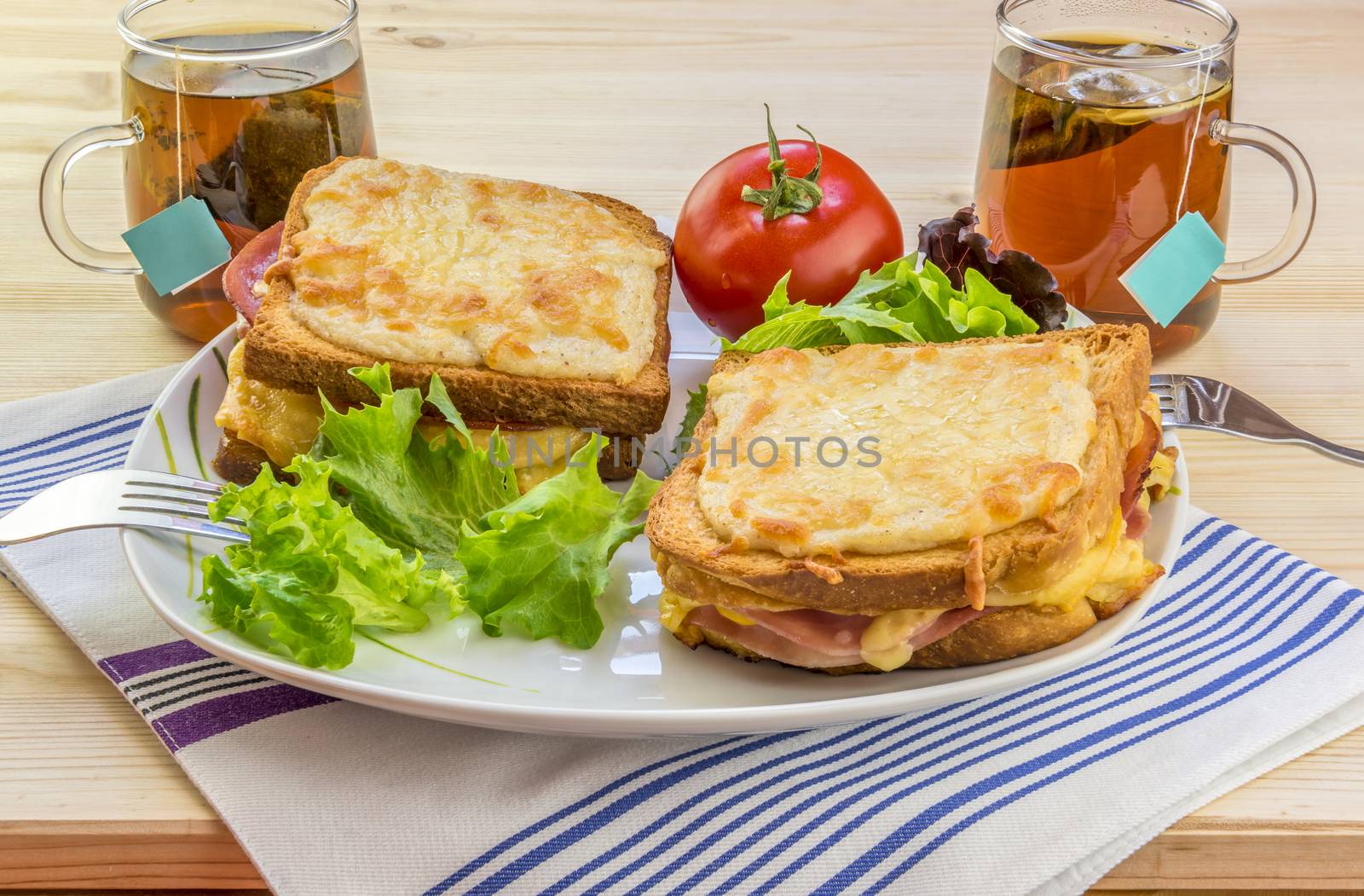 Appetizing food image with gratin cheese sandwiches, fresh salad and warm cups of tea, enough for two people.