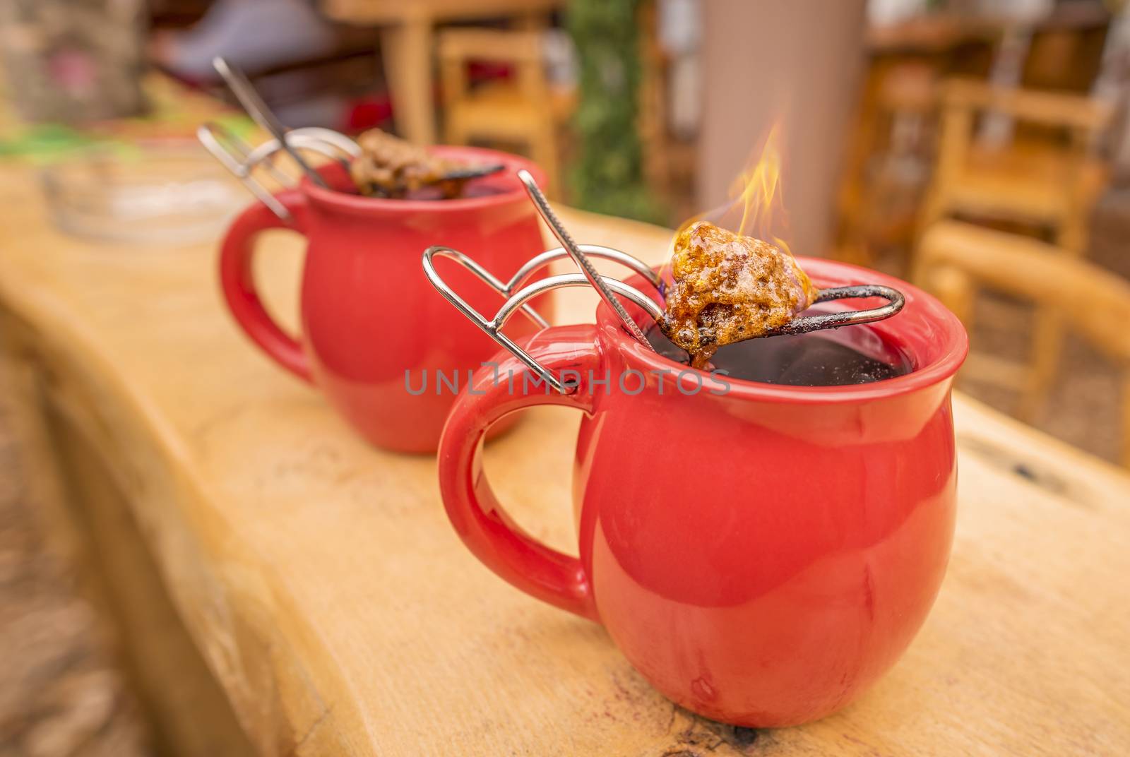 Image with a mug of hot wine, which has tongs with a flaming cone of sugar on top. It is a traditional german drink at Christmas fairs, called "Feuerzangentasse", meaning Fire Cup.