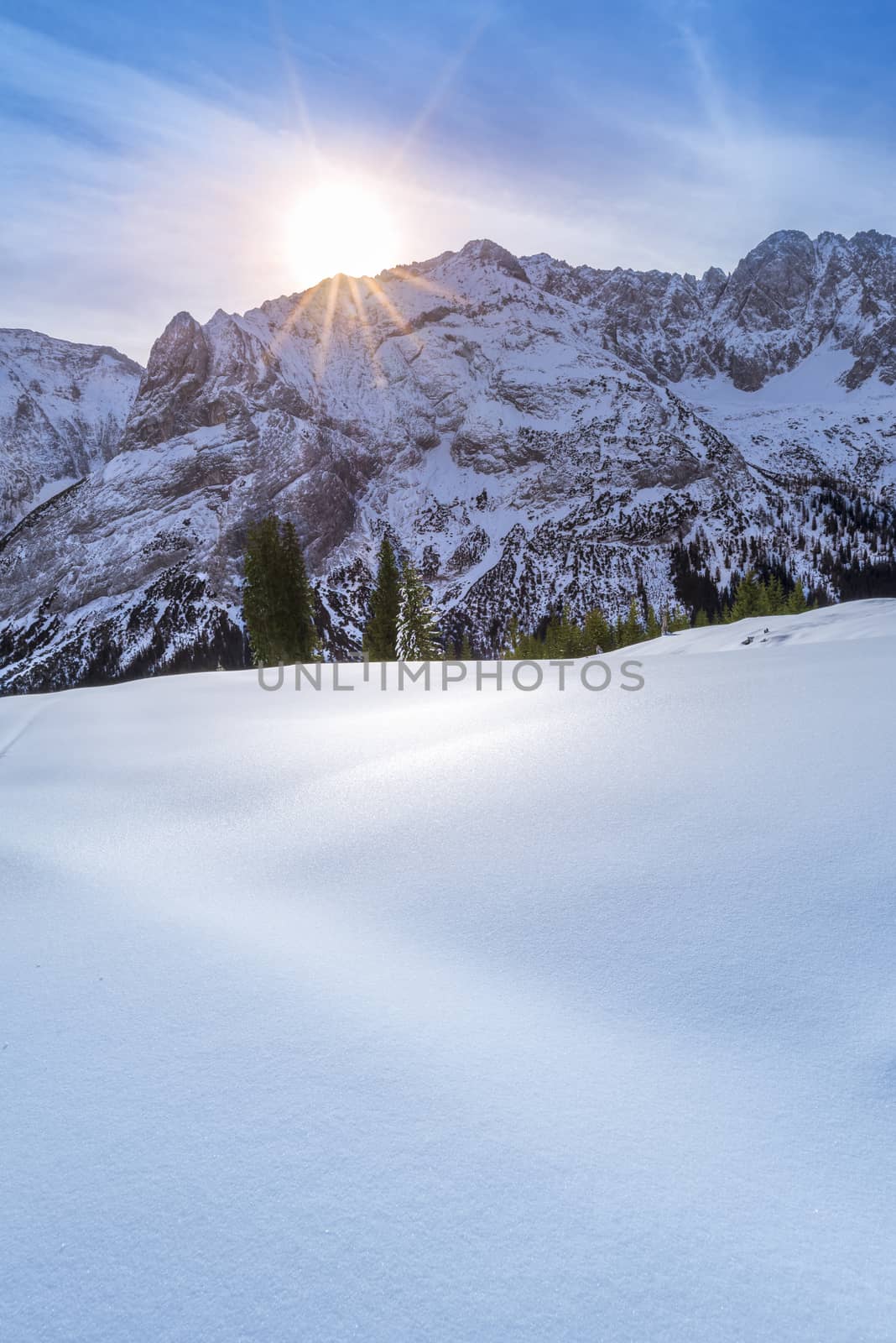 A lovely winter day in the Austrian Alps mountains from the Ehrwald municipality, with the rocky peaks and snowy pastures warmed up by a bright and colorful sun.