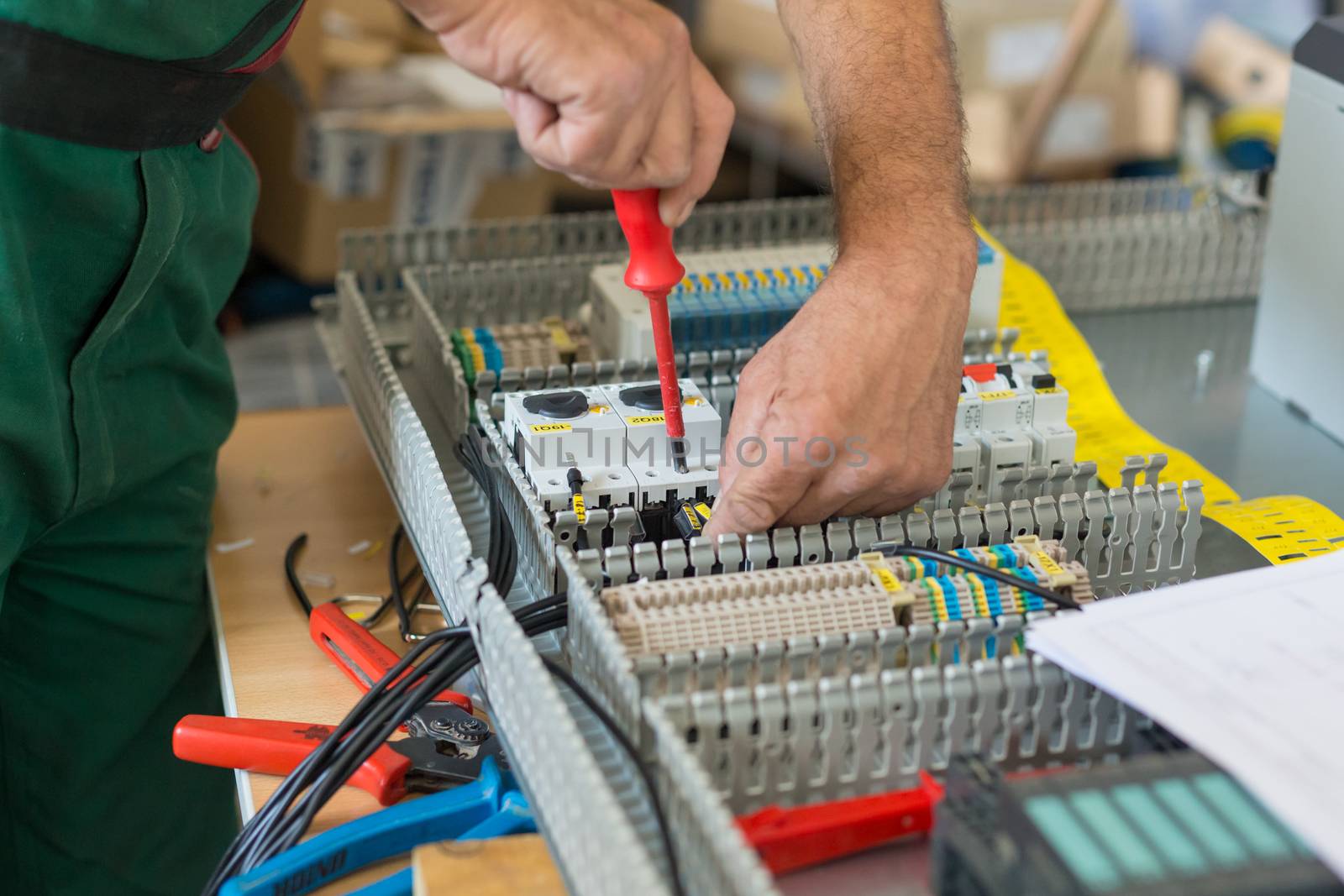 Electrician assembling industrial electric cabinet in workshop.