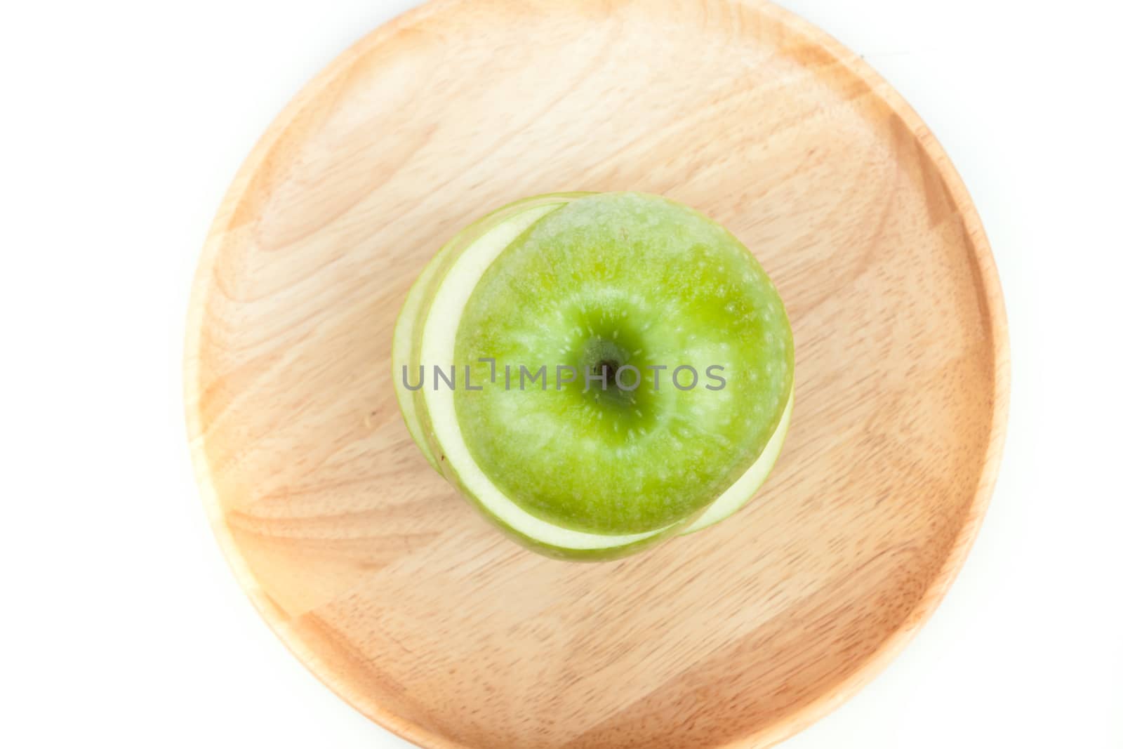 Sliced green apple on wooden plate on white background