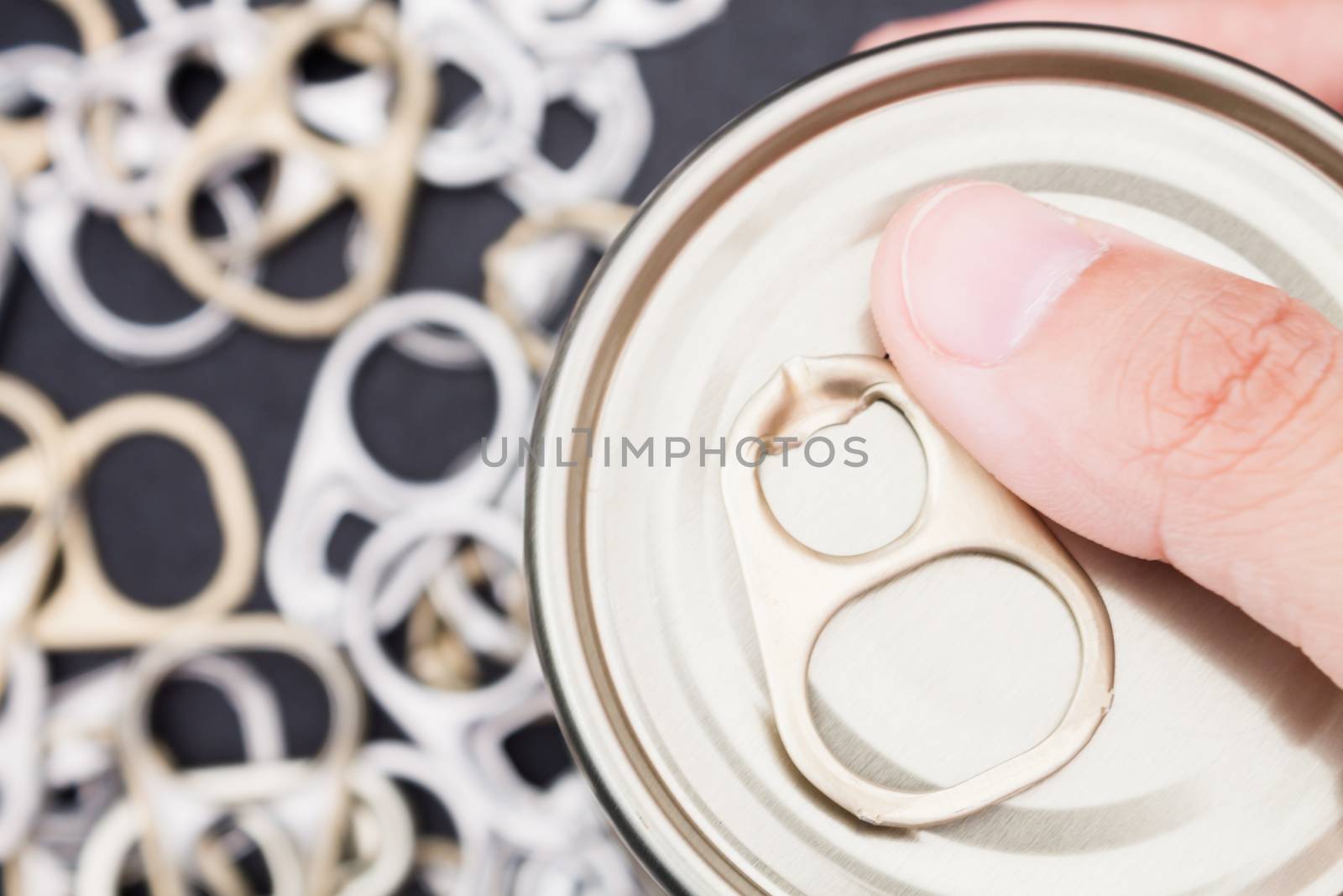 Woman hand holding ring pull cans opener on black metallic background