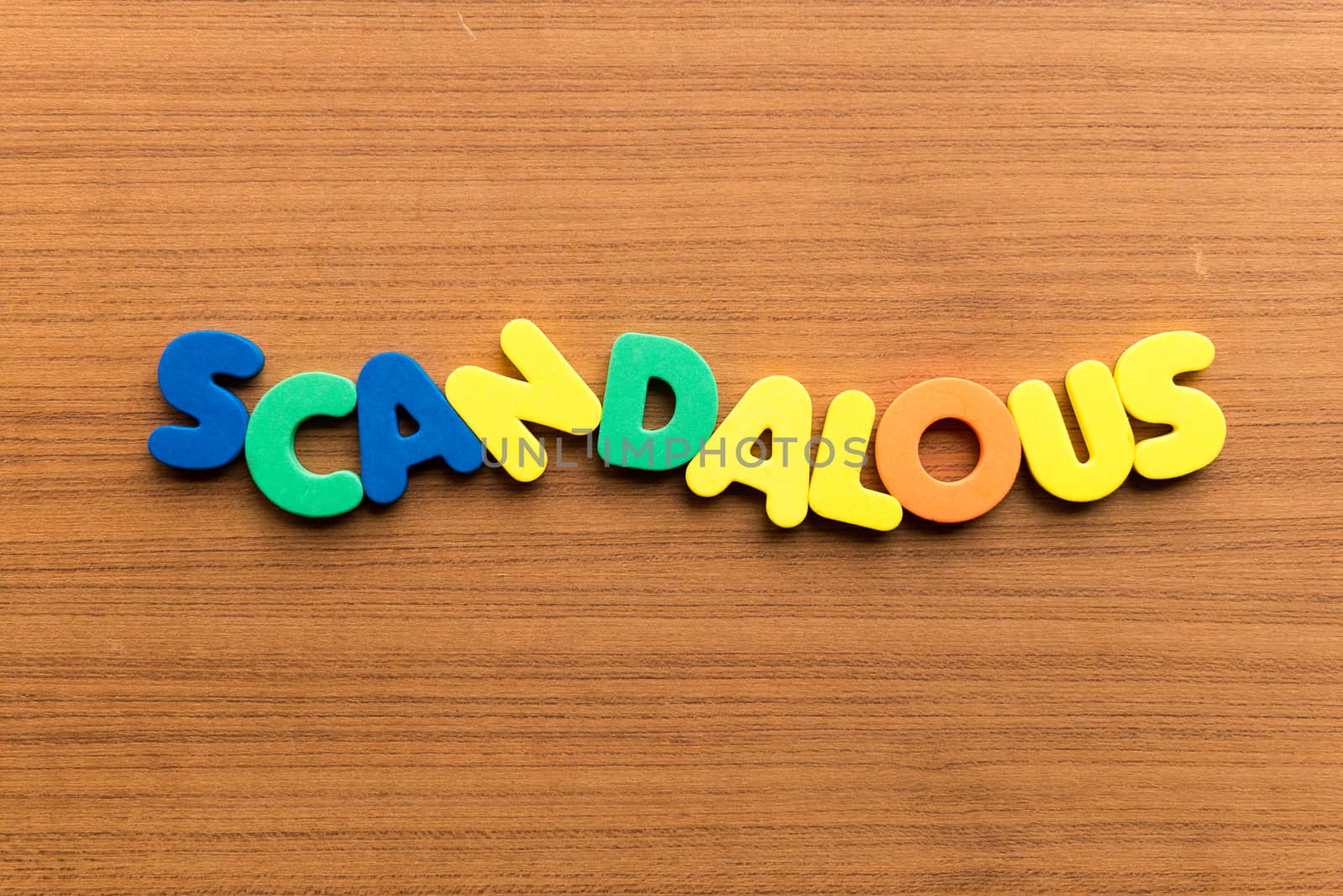 scandalous colorful word on the wooden background