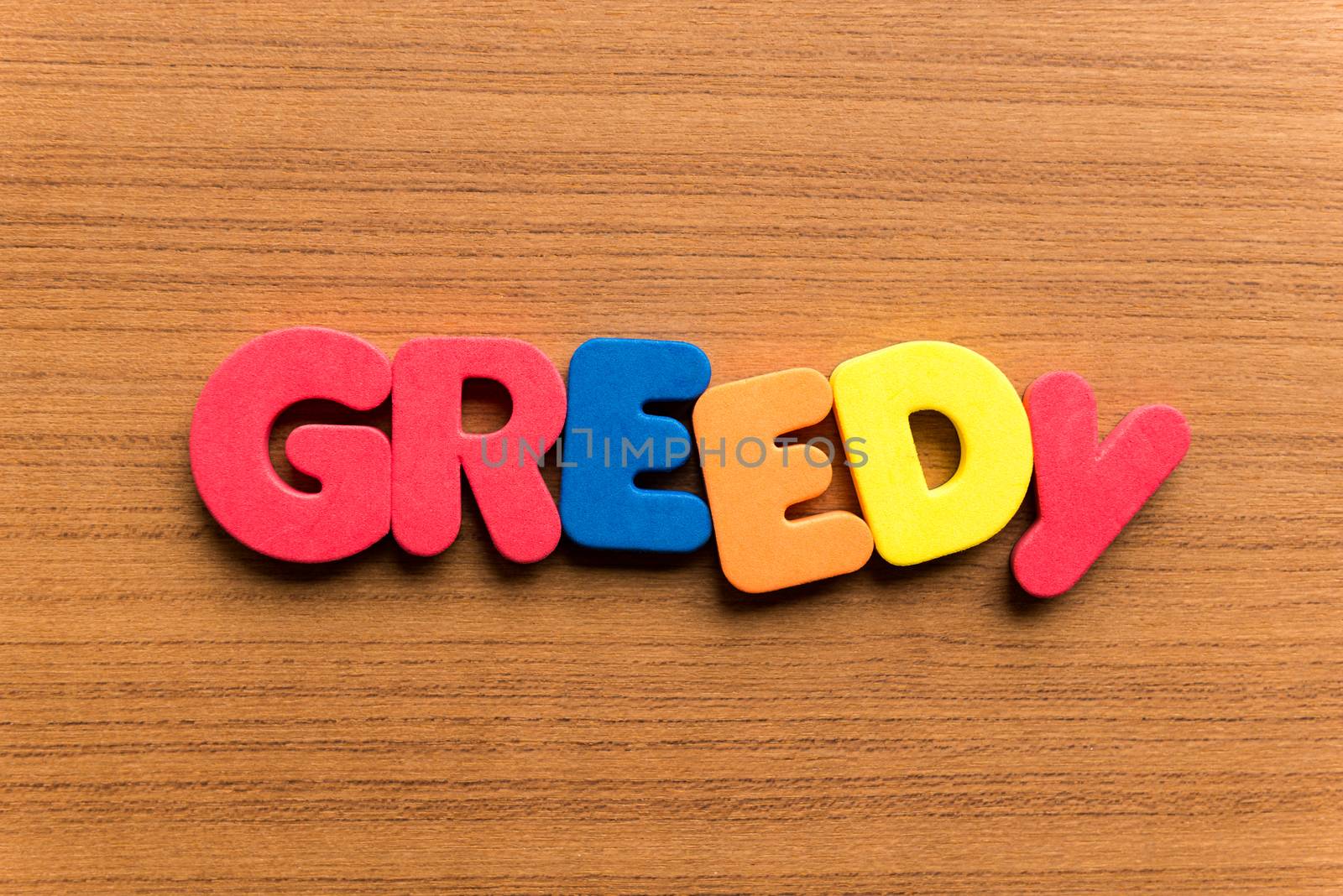 greedy colorful word on the wooden background
