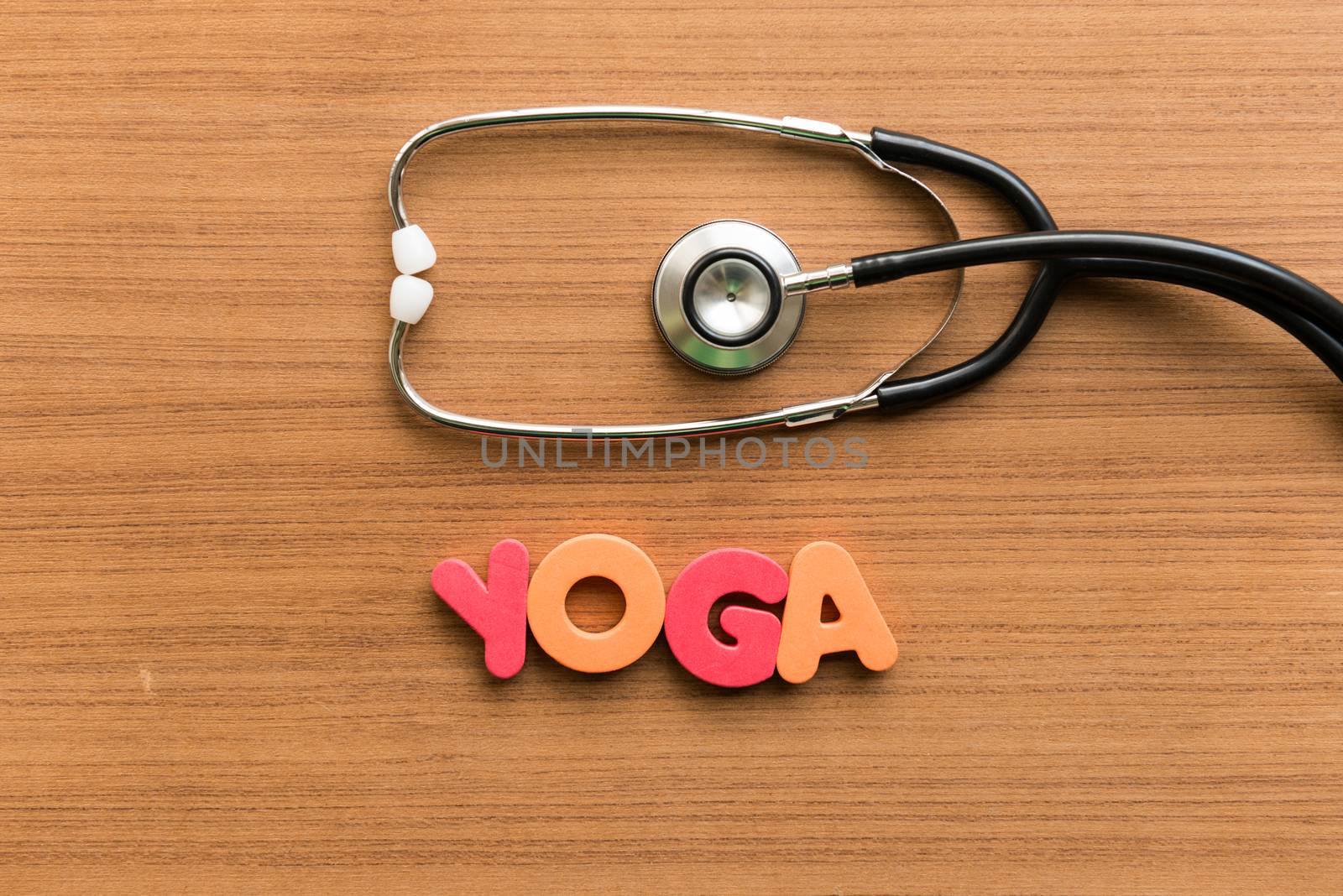 yoga colorful word with stethoscope on wooden background