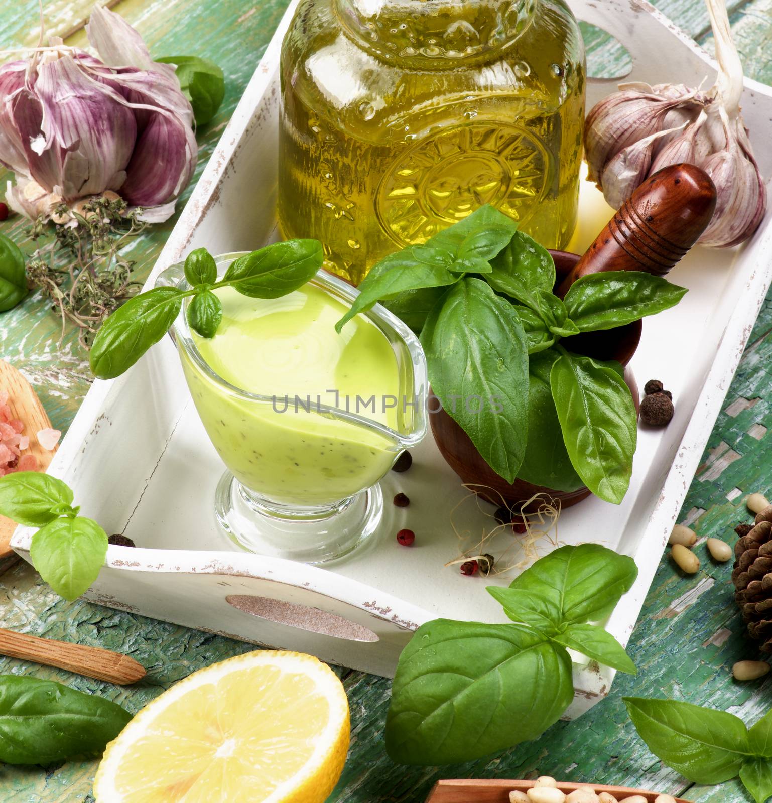 Freshly Made Creamy Pesto Sauce with Raw Fresh Ingredients and Olive Oil in White Wooden Tray closeup Cracked Wooden background