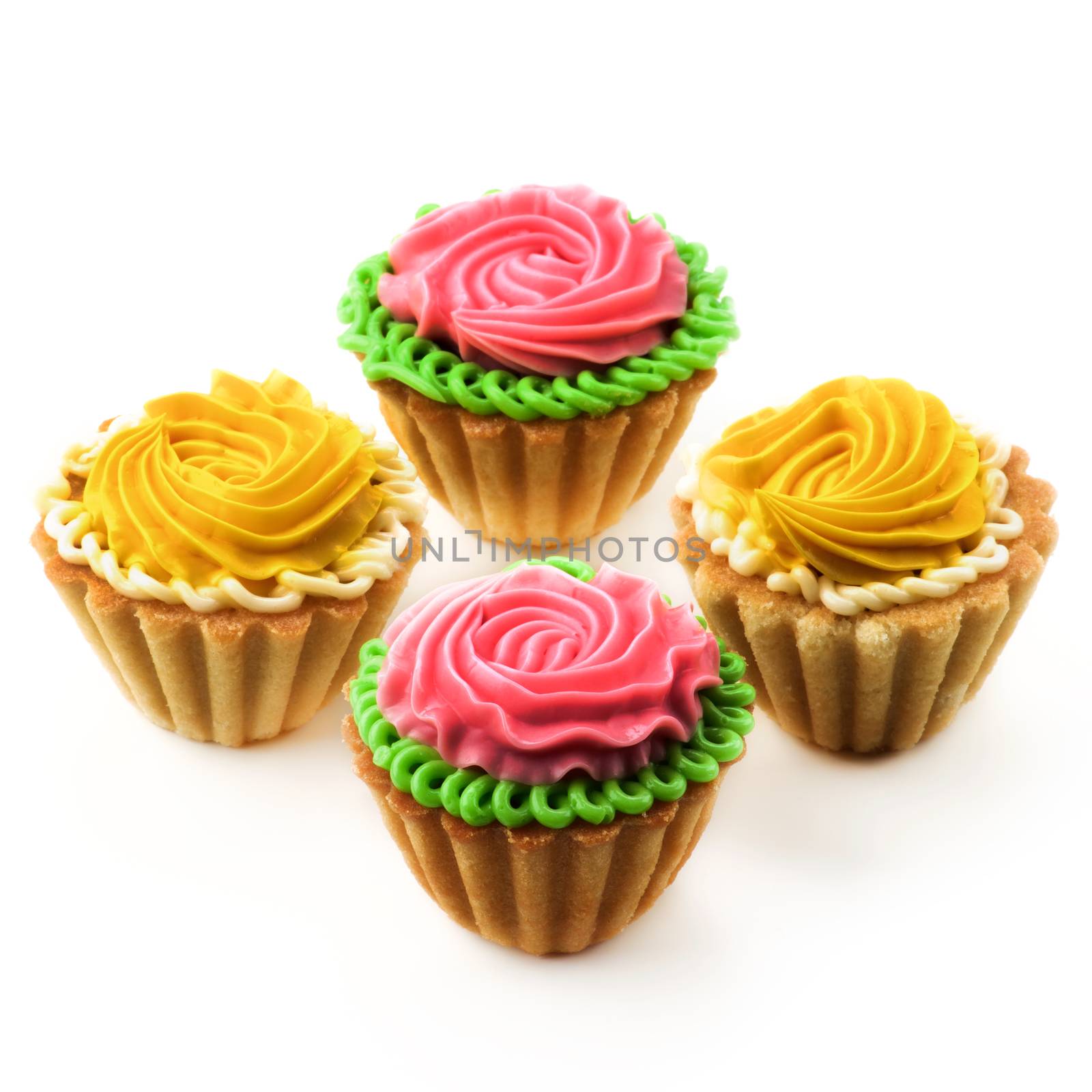 Arrangement of Delicious Little Tarts with Colored Butter Cream and Decoration closeup on White background