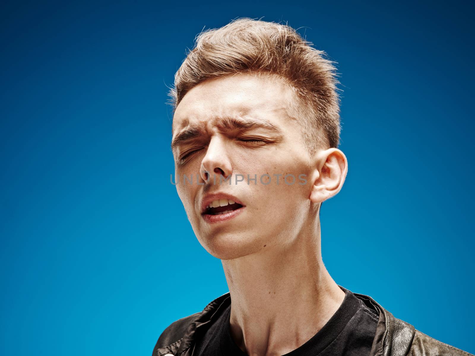 Emotional portrait of a teenager on a blue background