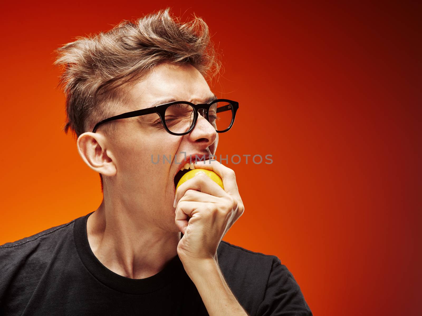 Emotional portrait of a teenager with lemon on a red background