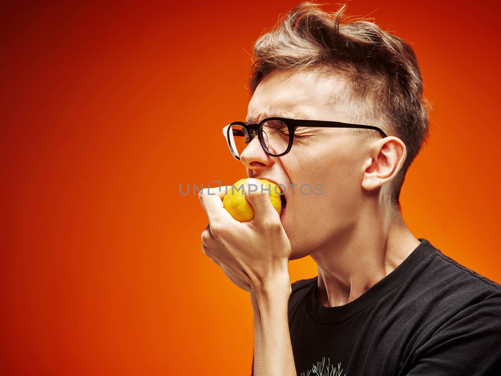 Emotional portrait of a teenager with lemon on a red background