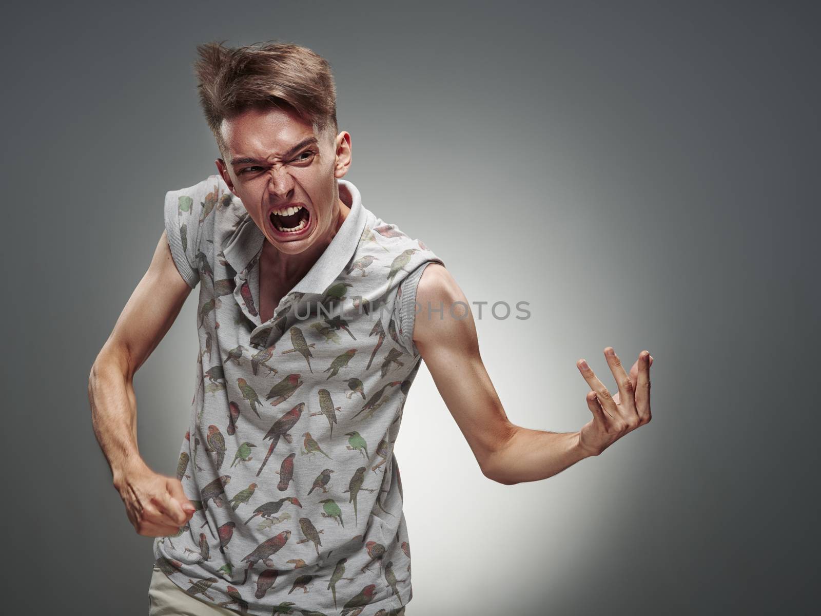 Emotional portrait of a teenager  playing on air guitar on a gray background