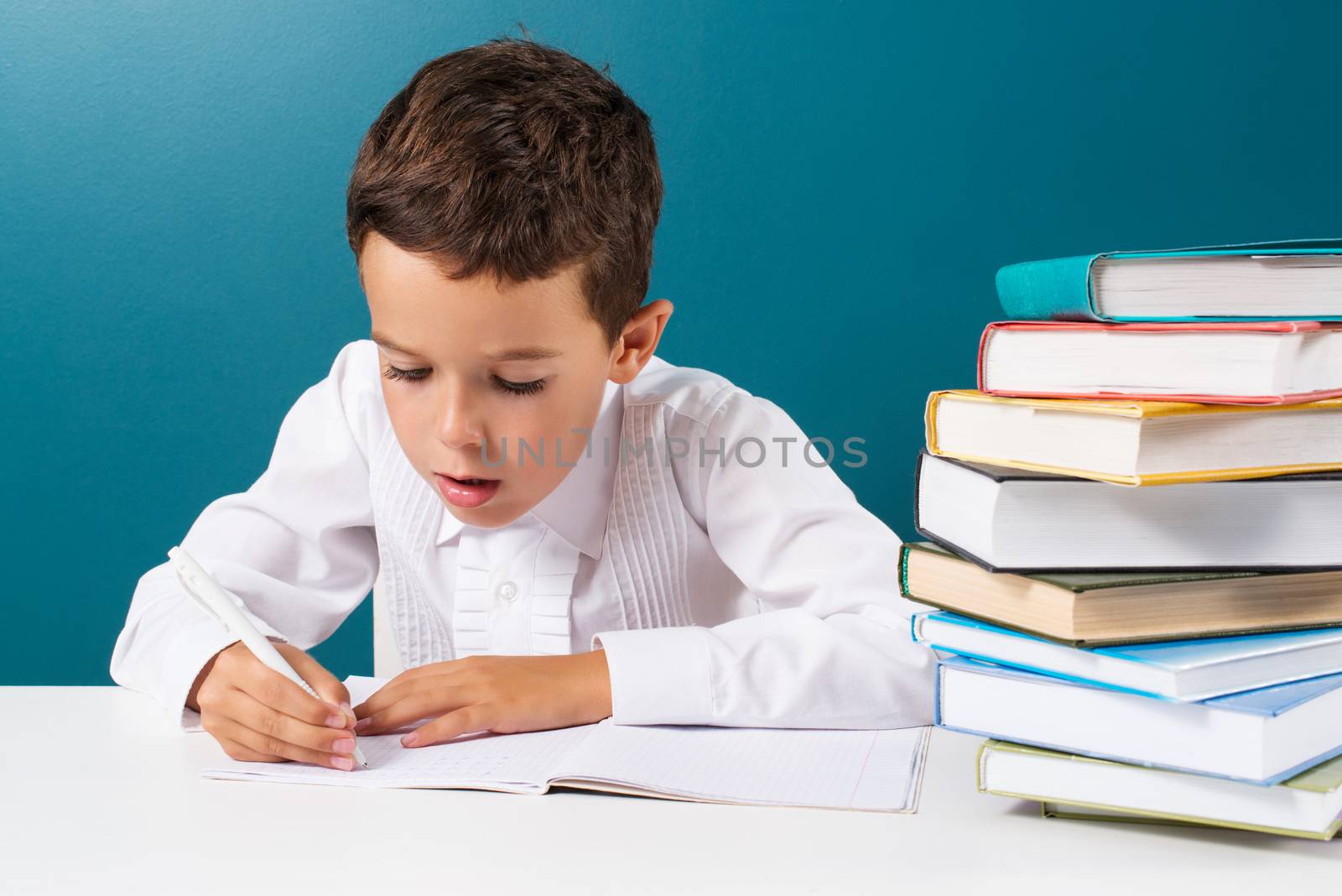 Pensive cute boy with homework sitting at a table by kzen