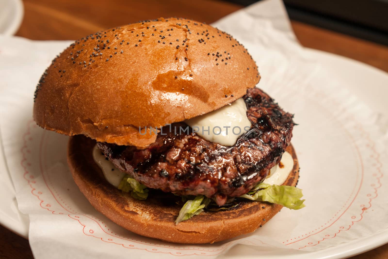 Fresh burger with beef and pork and special sauce closeup on wooden table.