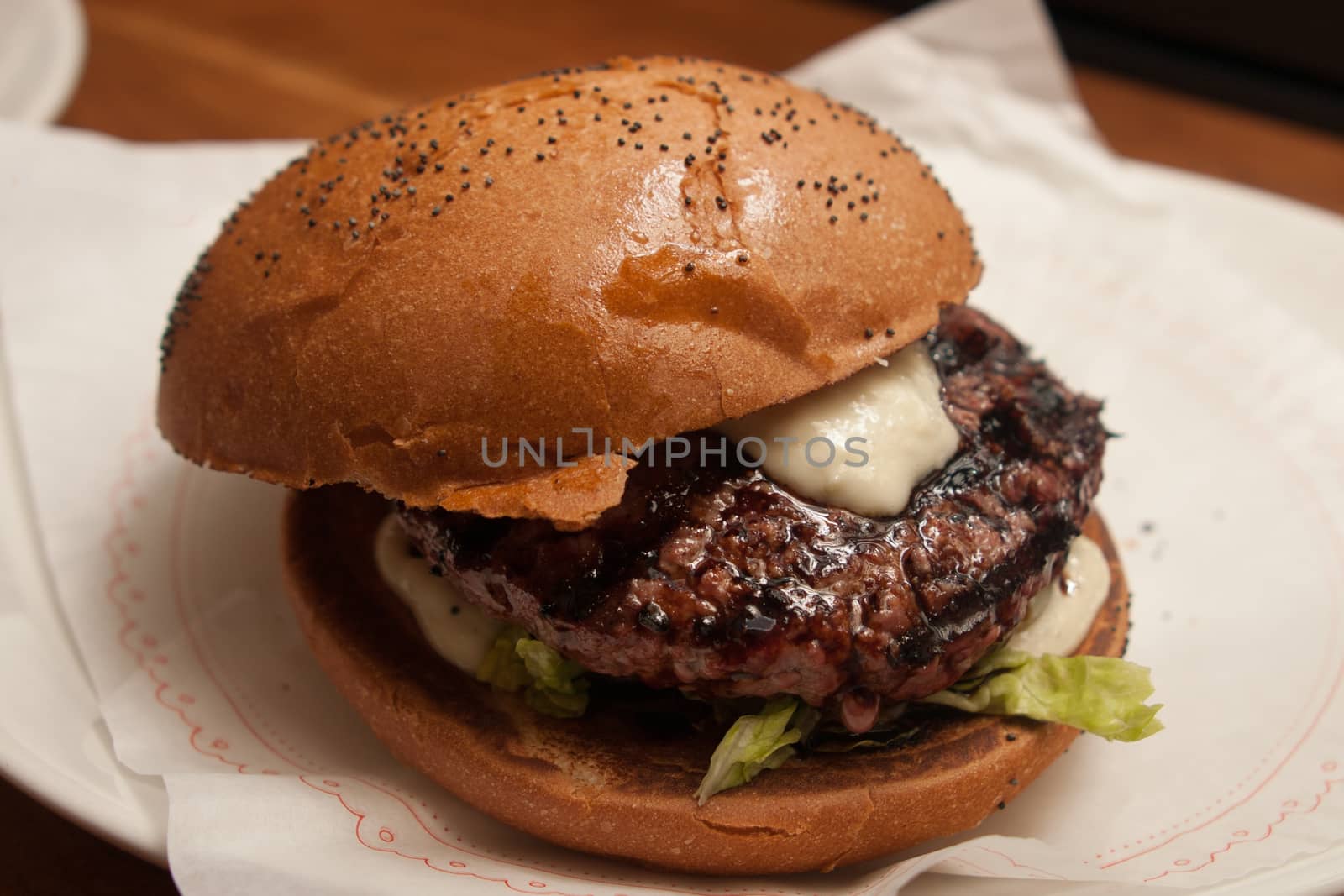 Fresh burger with beef and pork and special sauce closeup on wooden table.