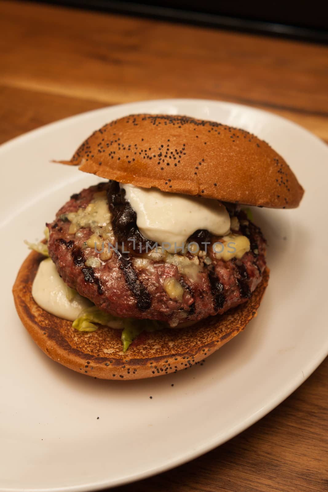 Fresh burger with beef and pork and special sauce closeup on wooden table.