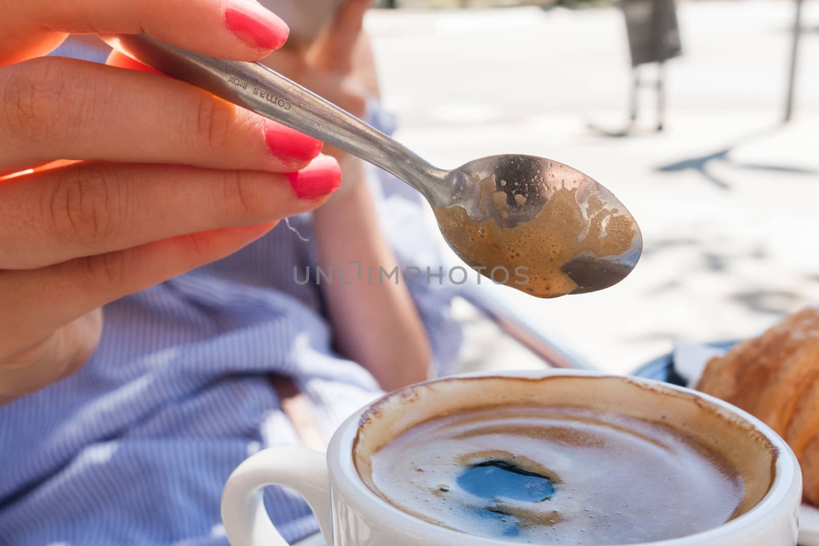 woman hand lower the spoon into the cup of coffee close up outdoor