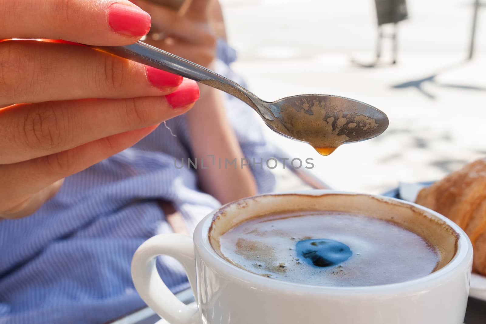 woman hand lower the spoon into the cup of coffee close up outdoor