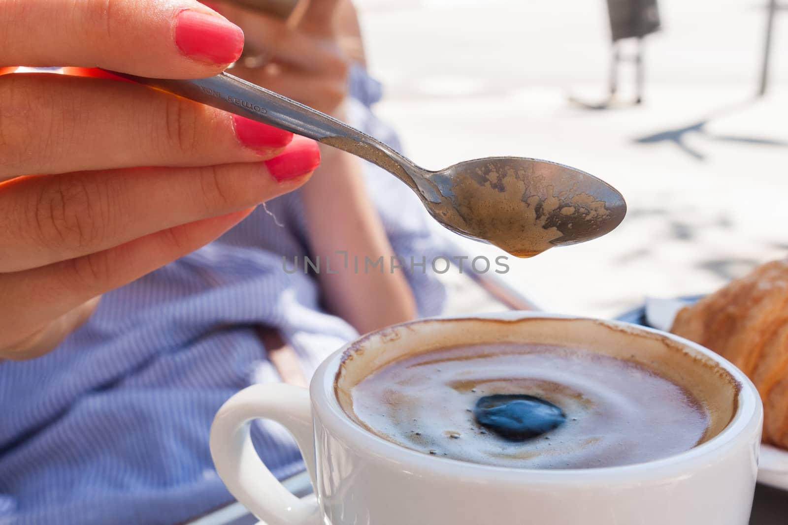 woman hand lower the spoon into the cup of coffee close up outdoor