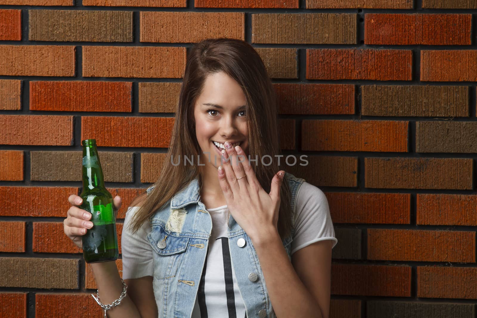 teen girl with surprise look, holding a green bottle of beer