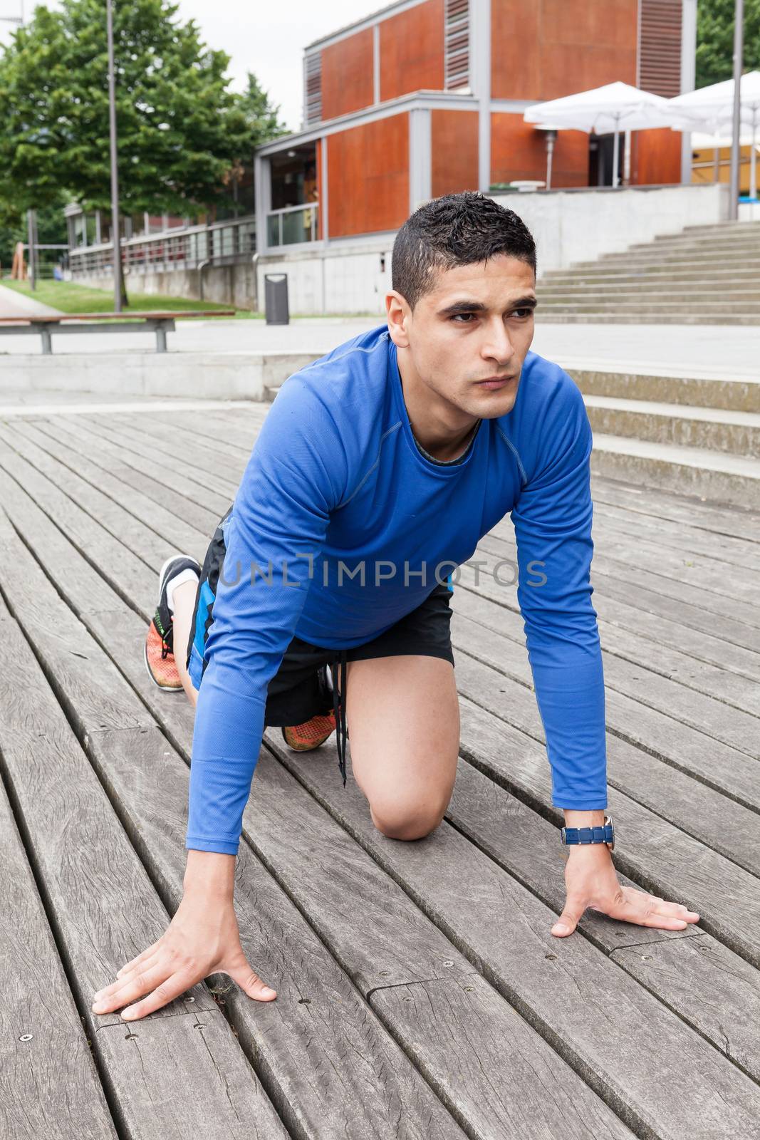 Young athlete in starting position sprint trainning in a wood floor outdoor