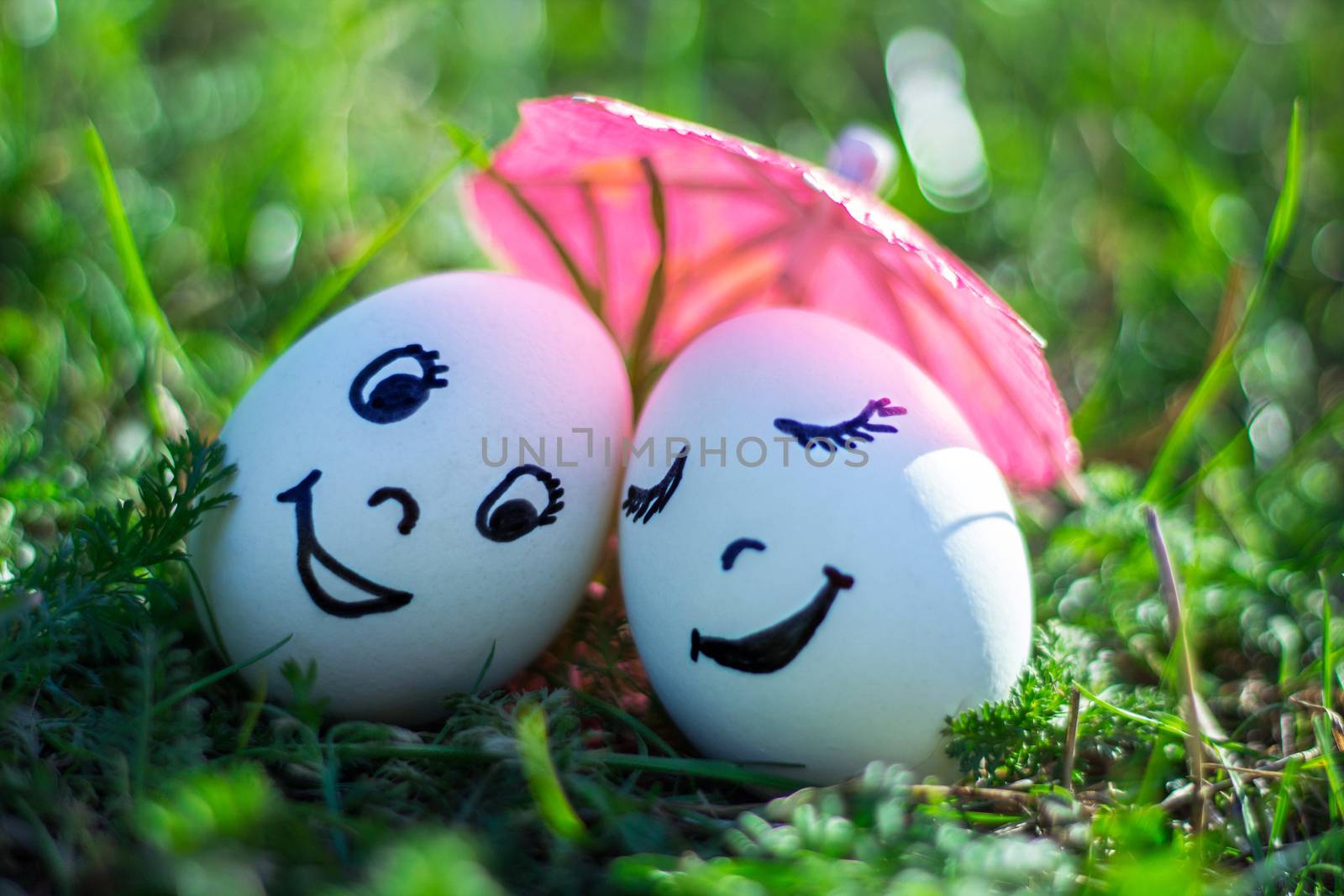Funny eggs imitating happy couple of lovers with smiling faces under umbrella