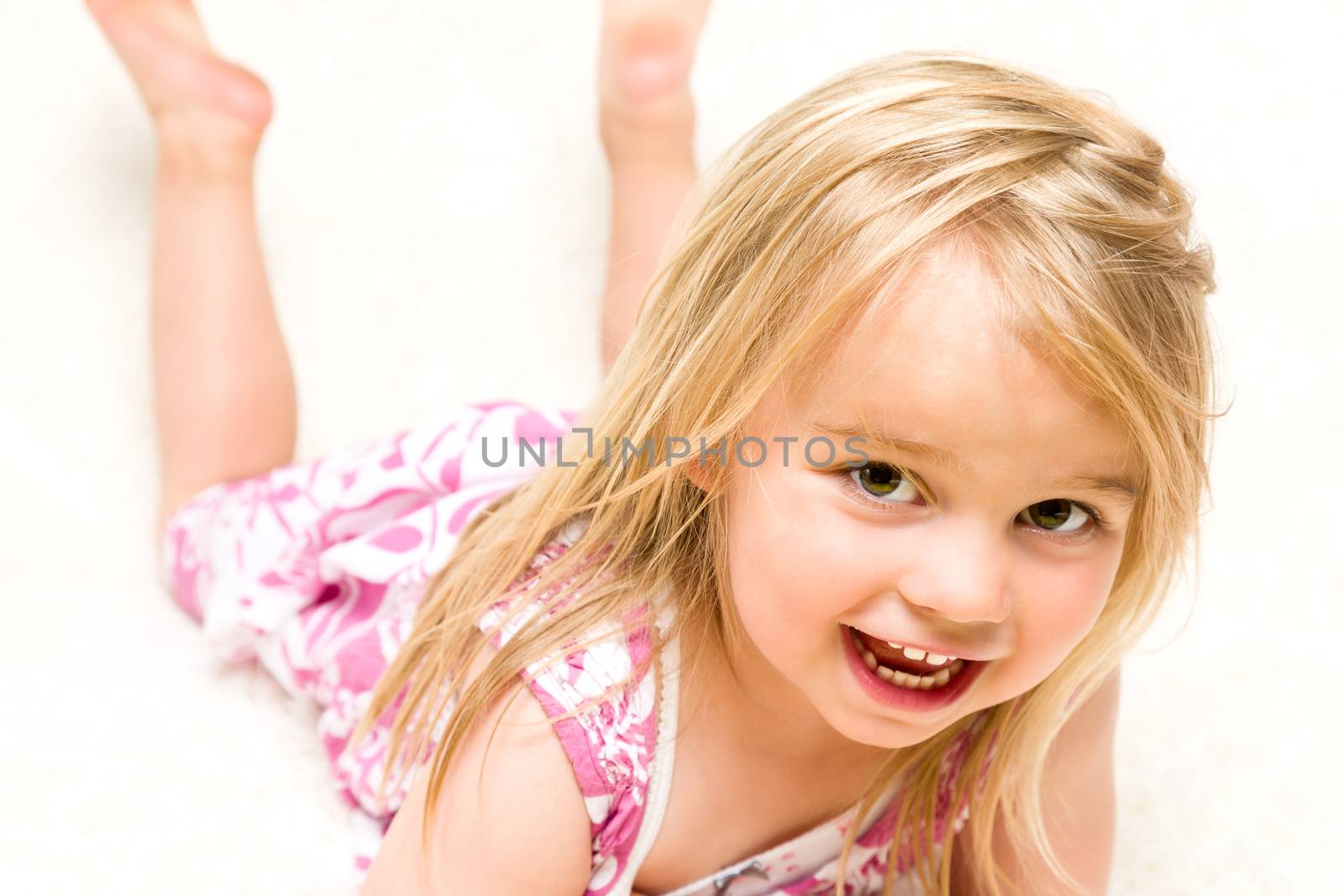 Closeup Portrait of Beautiful Toddler Girl Lying Down on Neutral Background