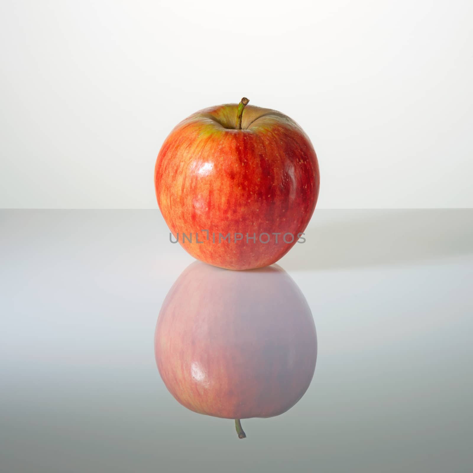 Red elastic apple on a surface with reflection