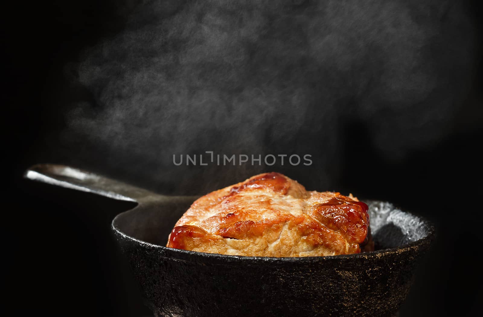 Pork fried on a cast iron skillet, a big piece. Black background and couples