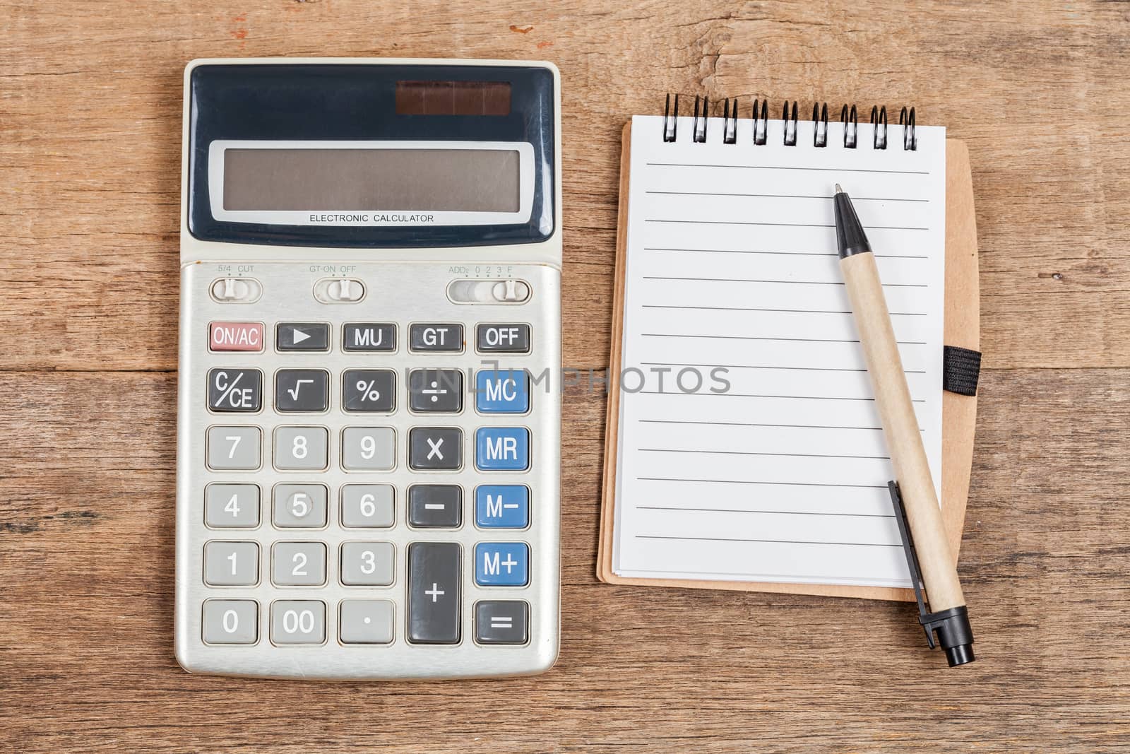 notebook showing empty page  and calculator on wooden desk