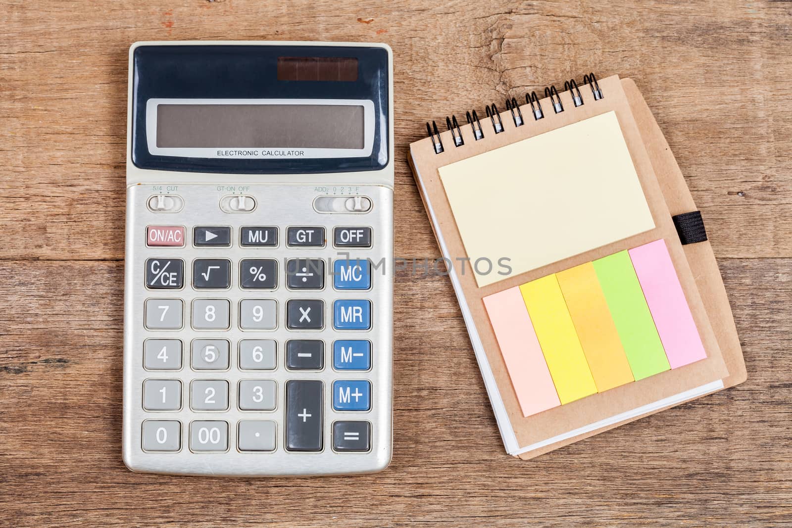 notebook showing empty page  and calculator on wooden desk