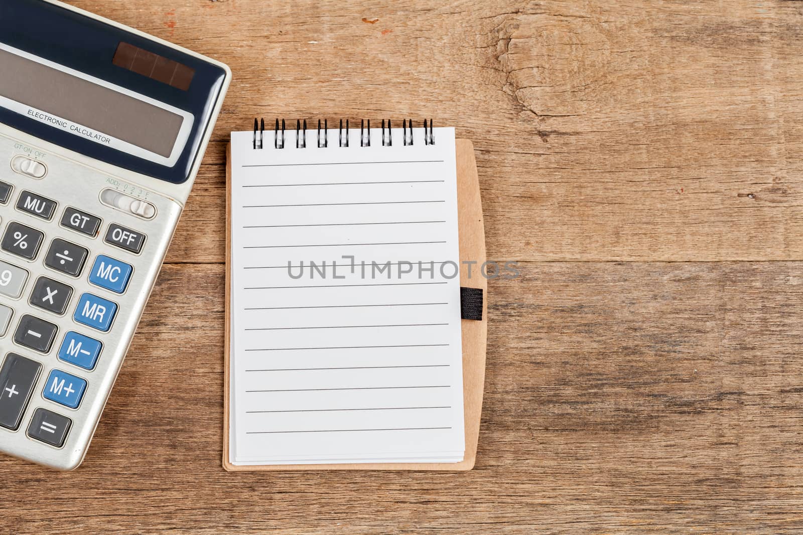 notebook showing empty page  and calculator on wooden desk