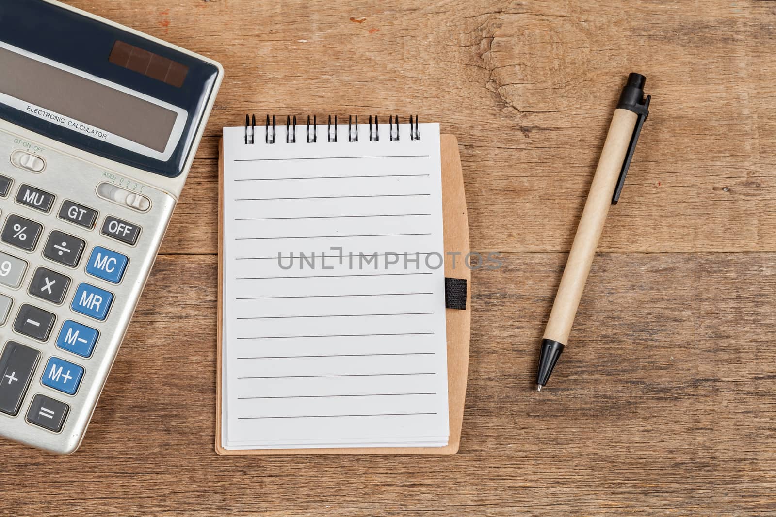notebook showing empty page  and calculator on wooden desk