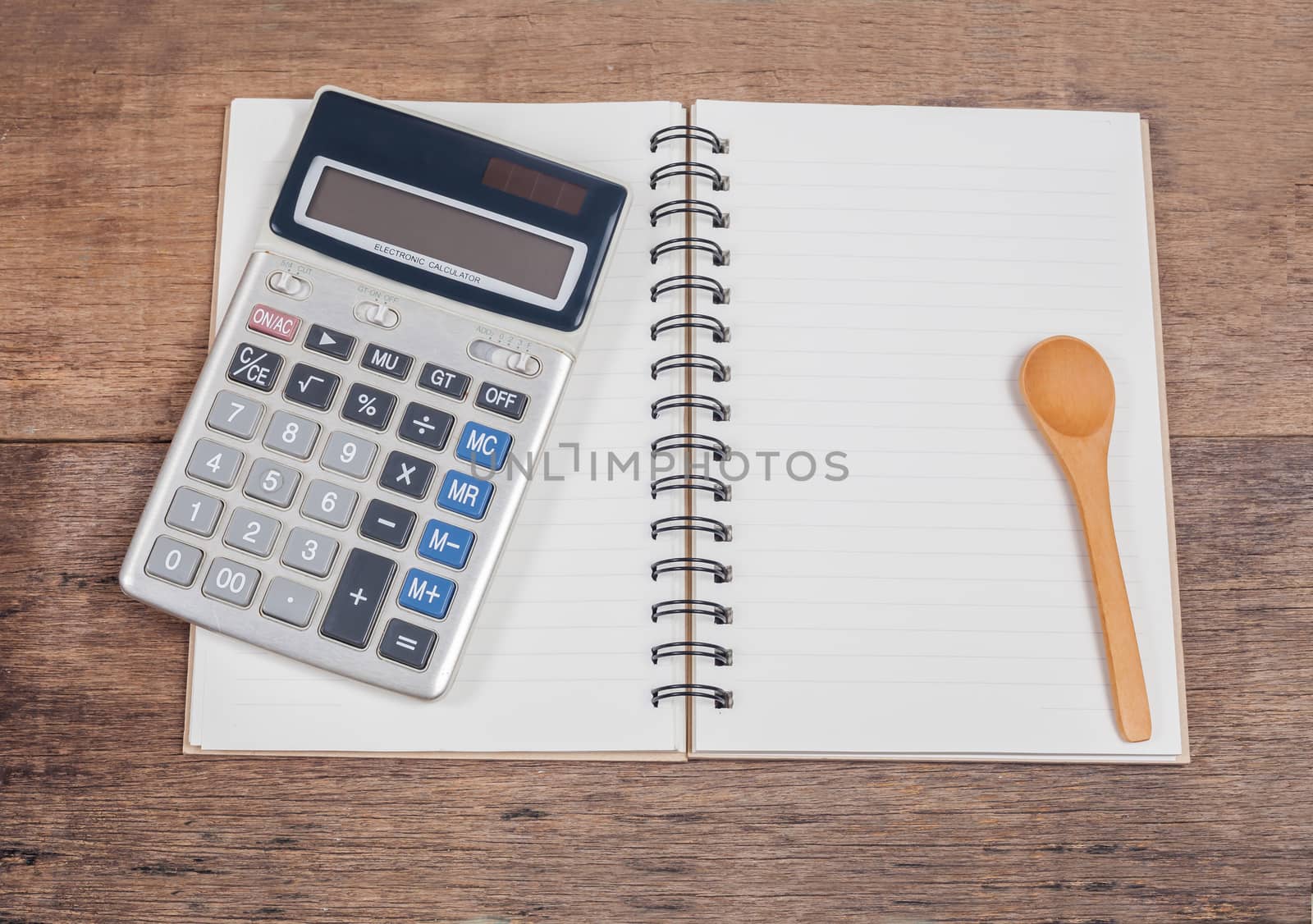 notebook showing empty page  and calculator on wooden 
desk