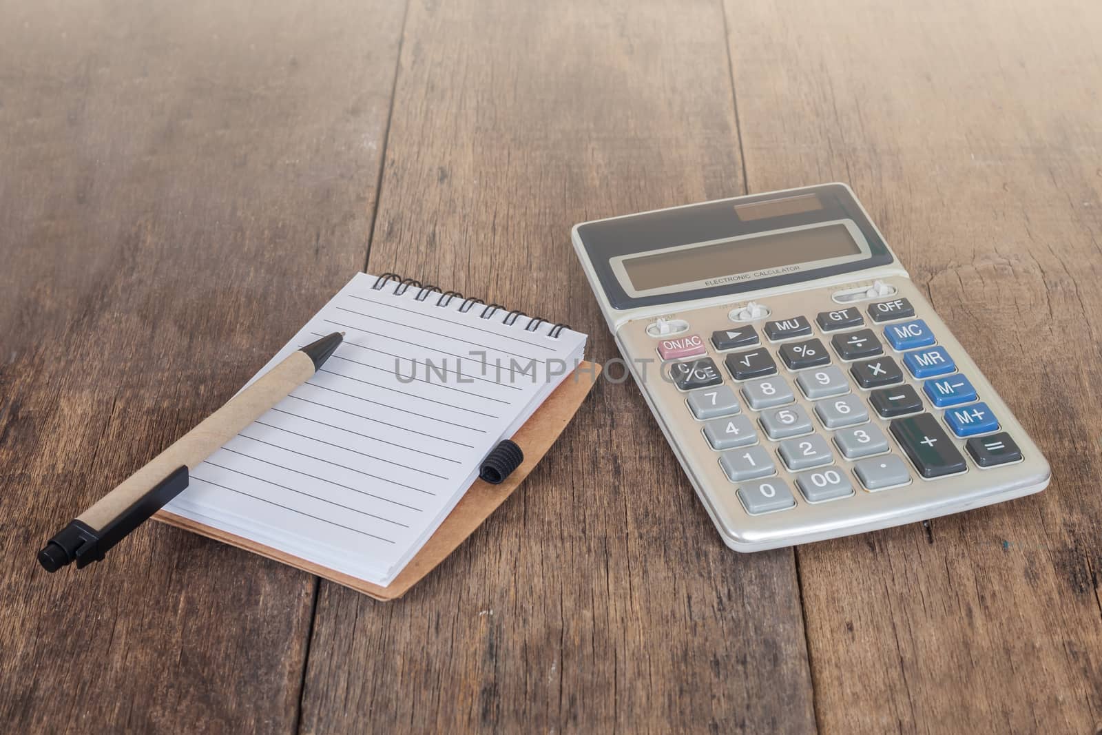 notebook showing empty page  and calculator on wooden 
desk