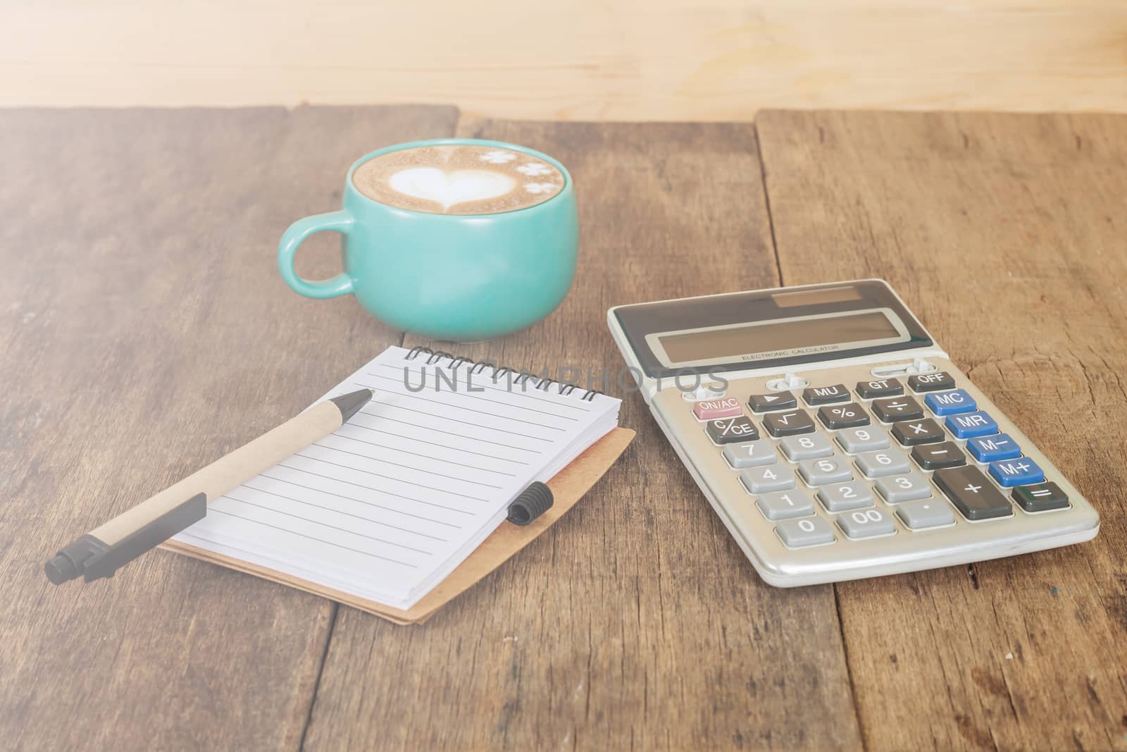 calculator, pen and cup of coffee on wood