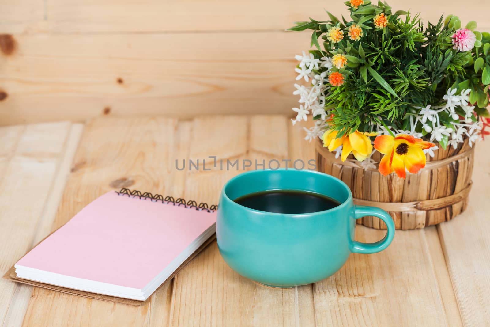 note book with cup and vase on wood table