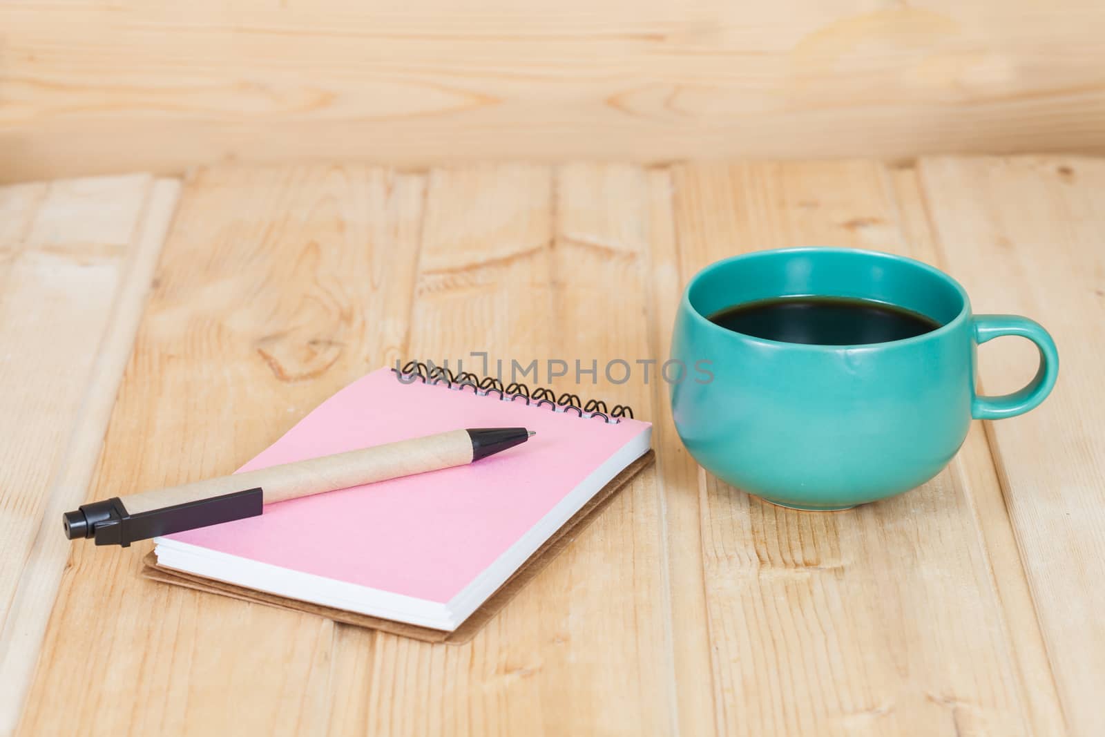 note book with cup and vase on wood table