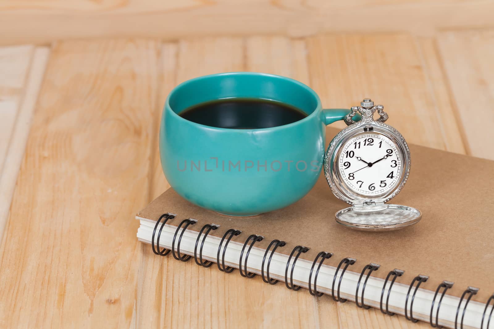 pocket watch and coffee cup on book