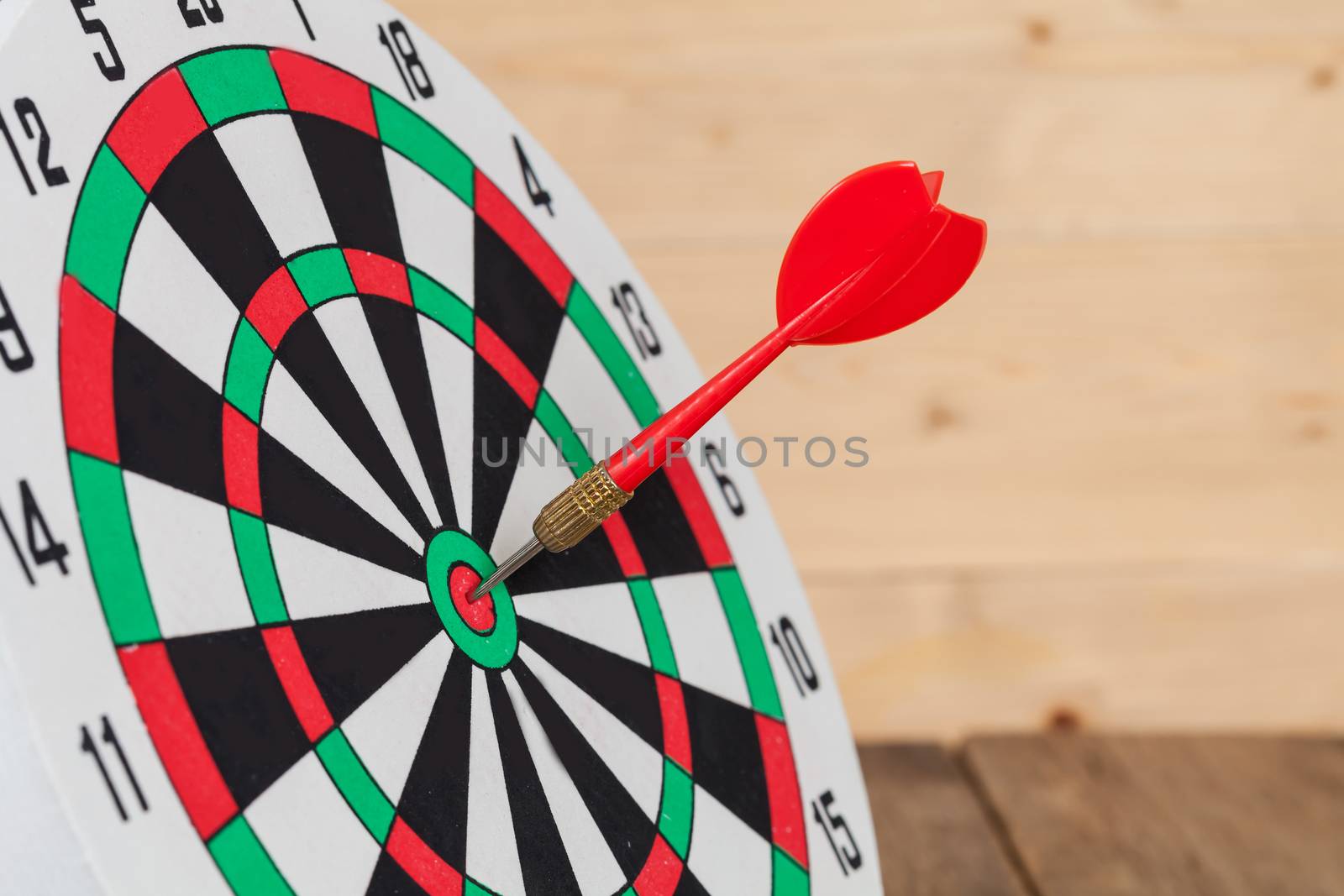 Dart arrow hitting in bullseye on dartboard
